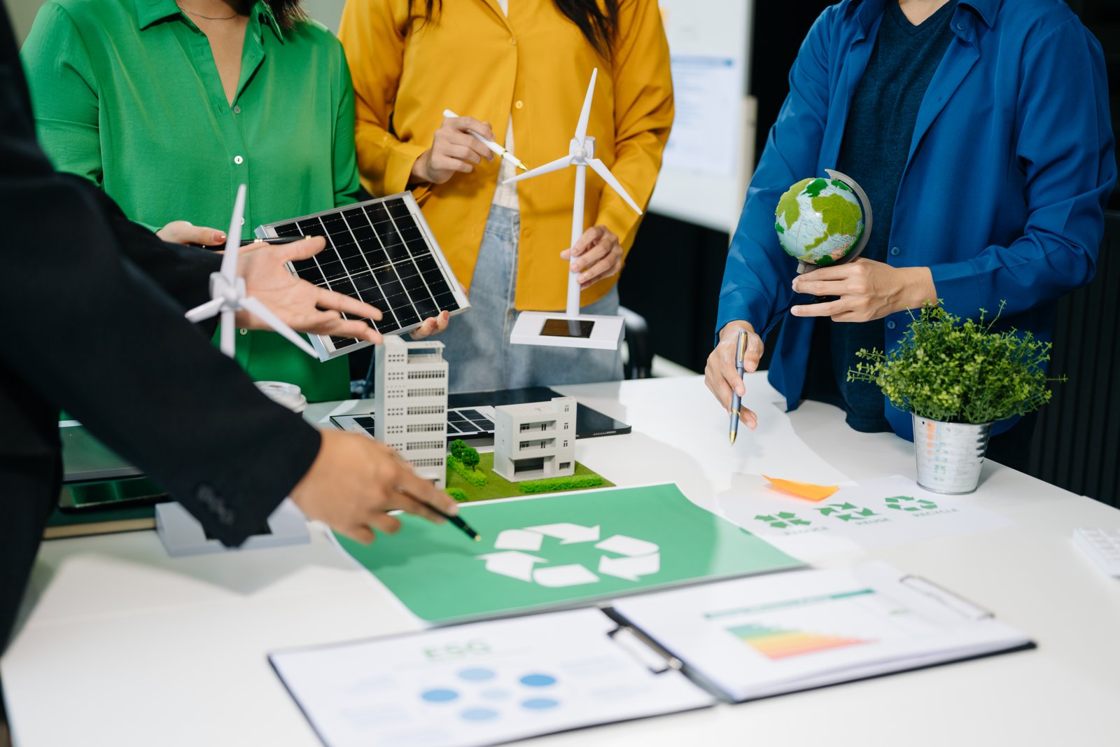 People discussing recycling and sustainability models with solar panels and wind turbines